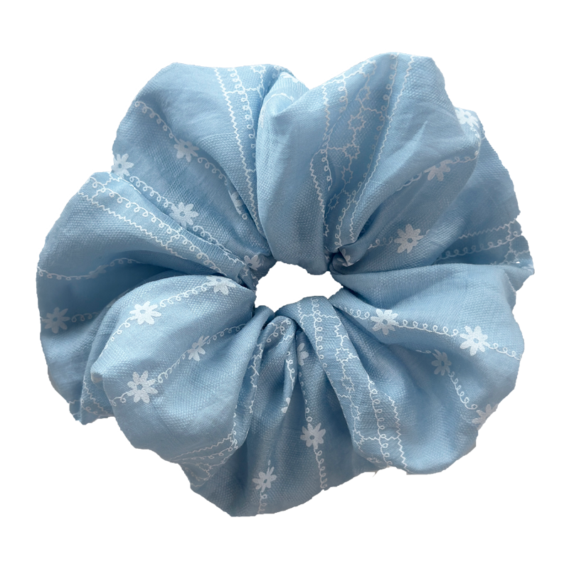 Front view of sky blue scrunchie with white daisy embroidery, breathable cotton hair tie for all hair types.