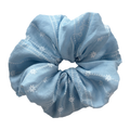 Front view of sky blue scrunchie with white daisy embroidery, breathable cotton hair tie for all hair types.