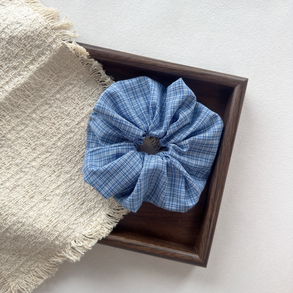 Blue checkered scrunchie on a wooden tray, stylish hair accessories for women.