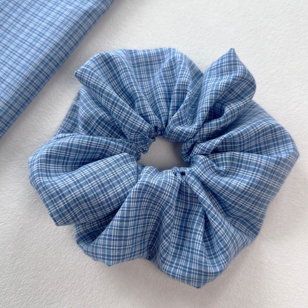 Close detail of a blue gingham linen scrunchie, showcasing high-quality cotton linen blend and texture.