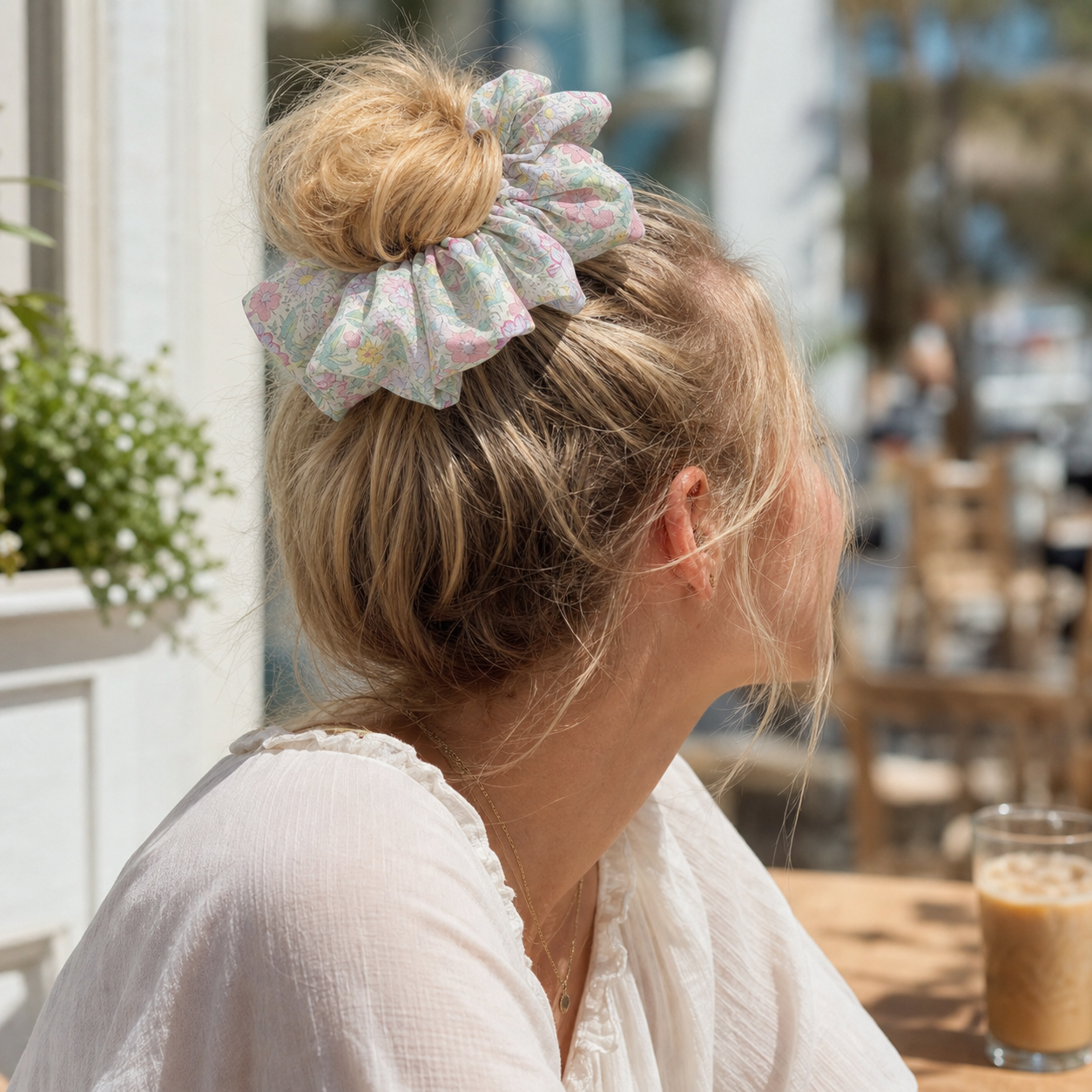 Blonde model in a messy bun with a multi-color floral scrunchie, mood-boosting accessory for an outdoor look.