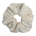 Single cream floral bouquet print scrunchie isolated on white background. Voluminous ruffled design with vertical ribbed texture, dusty pink blossoms, and soft frayed edges.