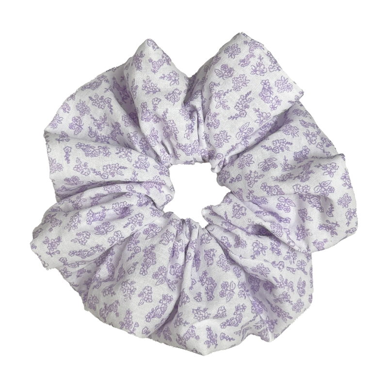 Single white scrunchie with delicate lavender floral print isolated on white background. Voluminous ruffled design with fine-line purple blossoms and leaves across a crisp cotton base.