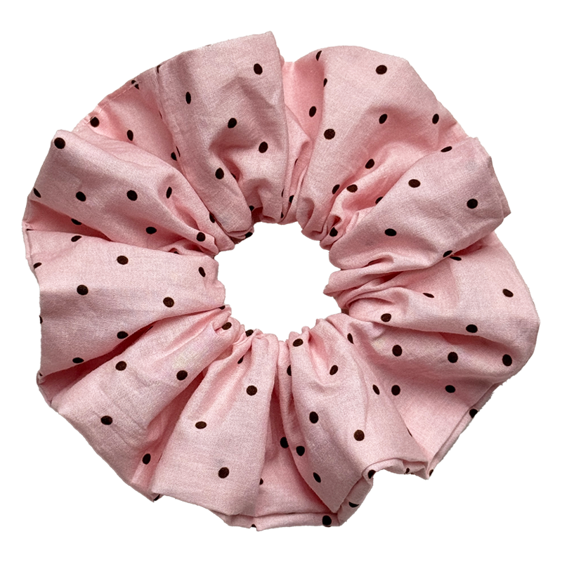 Single baby pink scrunchie with dark brown polka dots isolated on white background. Voluminous ruffled design with soft woven cotton texture and fine edge stitching.