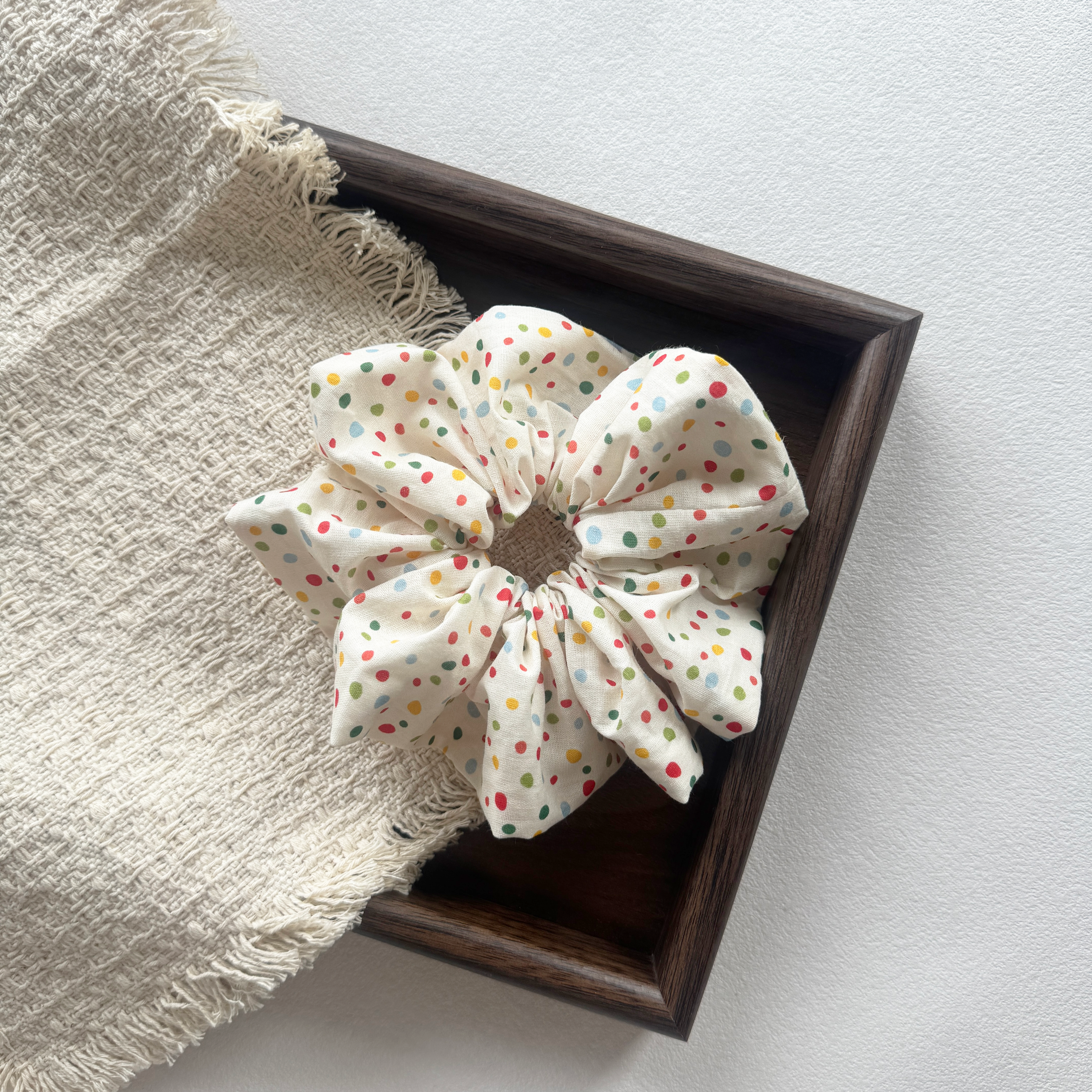 Detailed side view of a colorful polka dot linen scrunchie, handmade quality.