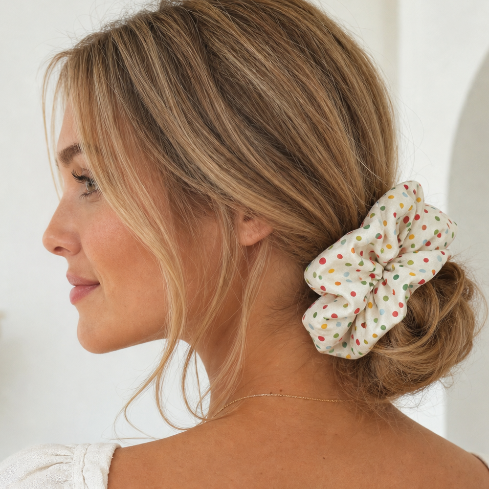 Model wearing a cream polka dot scrunchie in a low bun for hair protection.