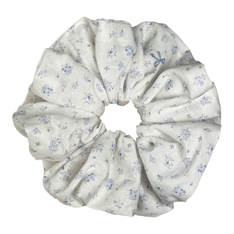 Single ivory dusty purple floral print scrunchie isolated on white background. Voluminous ruffled design with tiny flower clusters and a printed blue bow motif visible among the pattern.