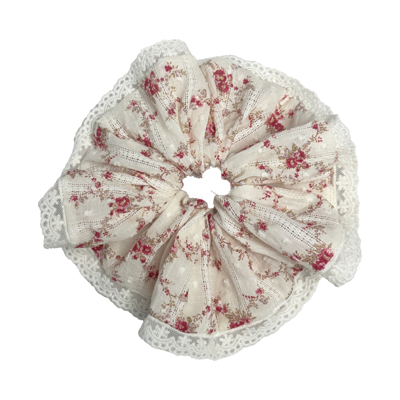 Single red floral lace scrunchie isolated on white background. Voluminous ruffled design with Swiss-dot fabric and scalloped white lace edge.
