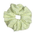 Single pastel yellow polka dot scrunchie isolated on white background. Voluminous ruffled design with deep folds.