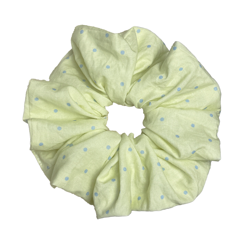 Single pastel yellow polka dot scrunchie isolated on white background. Voluminous ruffled design with deep folds.